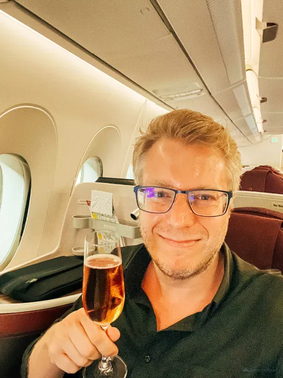 Fabian Hilpert in der Business Class mit einem Glas Champagner